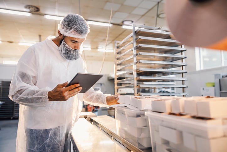 A food factory supervisor using tablet and assesses quality of food