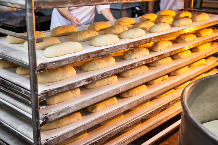 A rack full of loaves on baking sheets in a bakery facility.