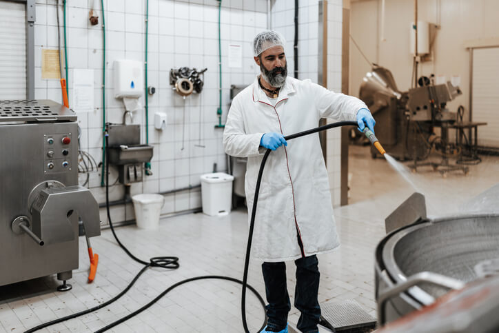 Butcher completing a food safety monitoring task by cleaning butchery equipment with a hose.