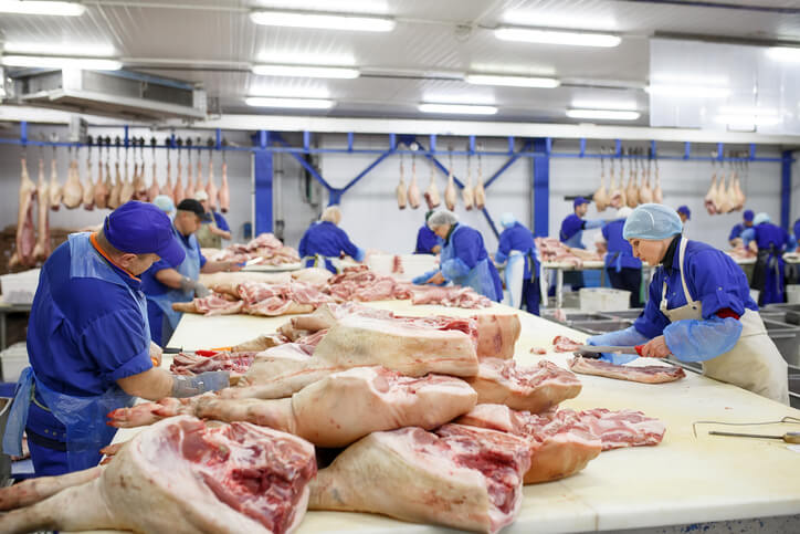 Team of butchers preparing cuts of meat to be sold out of their butcher shop.