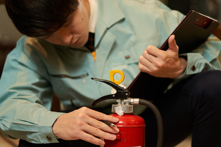 Fire department inspector inspecting a restaurant fire extinguisher.