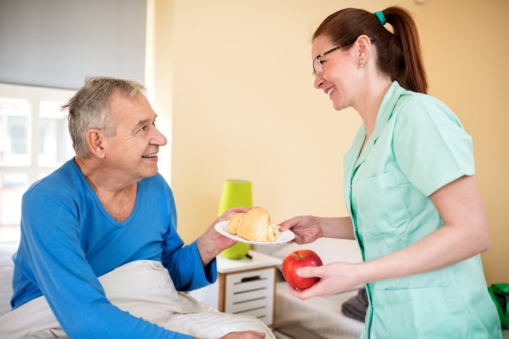 Happy old senior man looking at careful nurse