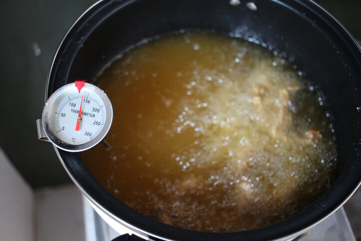 Kitchen thermometer checking food safety temperatures of soup broth.