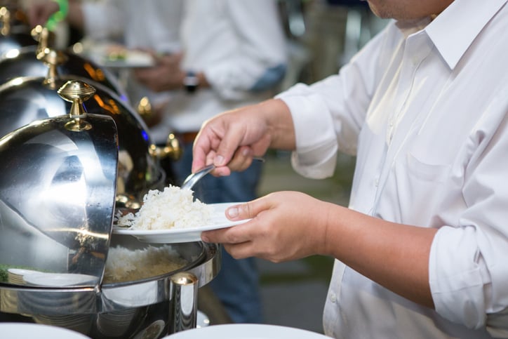 Man are scooping food from chafing dishes on the table at the luxury banquet