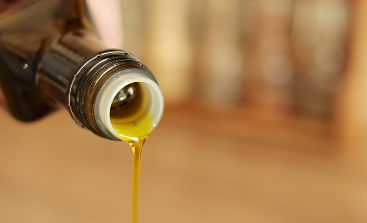 Pouring olive oil from glass bottle. Bottle Neck of Olive Oil Pouring Down a Macro Shot