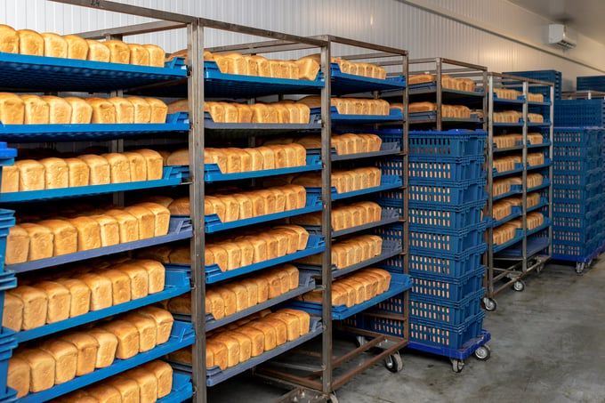 Racks with fresh bread in warehouse in industrial bakery