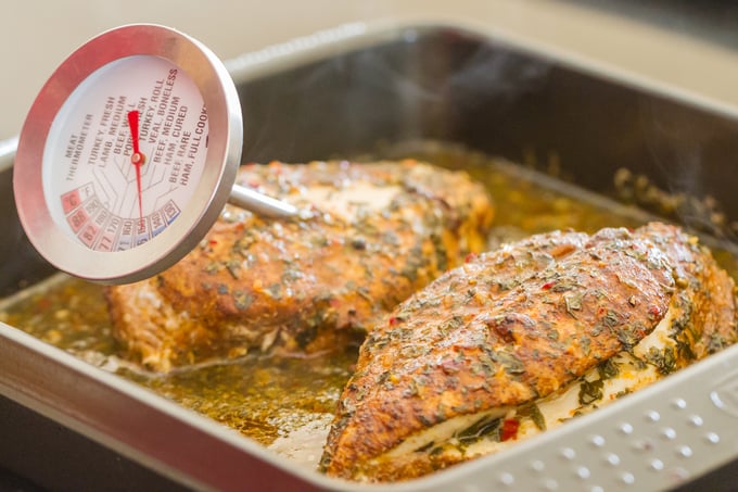 Taking the temperature of two seasoned chicken breasts