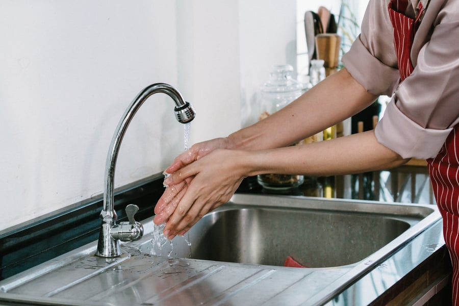 The cook is washing his hands in the sink