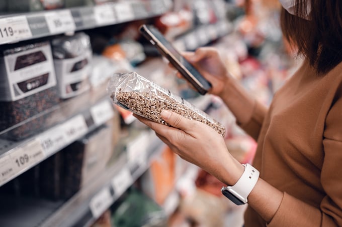 Woman shopping in supermarket and reading product information