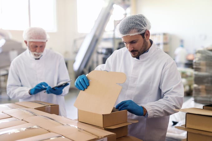Young Caucasian employee in sterile uniform packing goods in boxes